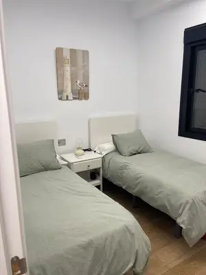 a bedroom with two beds and a table with a mirror at Apartamento con piscina en el Paseo Cruz del Mar in Chipiona