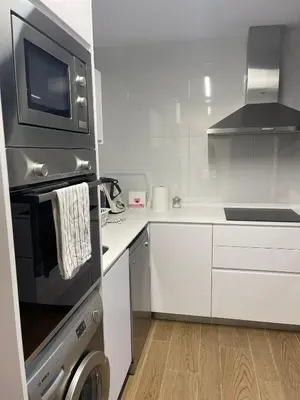 a kitchen with a stove and a microwave at Apartamento con piscina en el Paseo Cruz del Mar in Chipiona
