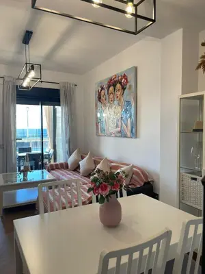 a living room with a table with a vase of flowers on it at Apartamento con piscina en el Paseo Cruz del Mar in Chipiona