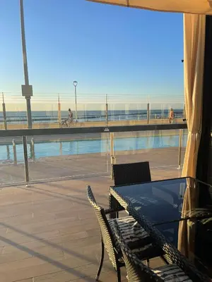 a patio with a table and chairs next to a pool at Apartamento con piscina en el Paseo Cruz del Mar in Chipiona