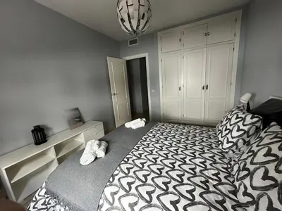 a bedroom with a bed with a black and white comforter at BASTINAZO ALOHADREAM - PREMIUM - La mejor ubicación con Aire Acondicionado, Insonorización, Terraza y Equipamiento en El Puerto de Santa María - Grupo de solo menores de 25 no aceptados salvo fianza adicional in El Puerto de Santa María