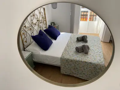 a mirror reflecting a bedroom with a bed with blue pillows at Azvalia - Puro Puerto Casco Histórico in El Puerto de Santa María