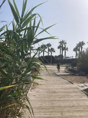 a person walking down a wooden boardwalk on the beach at Hochwertiges Haus in wunderschöner Golf Anlage am Meer in Rota