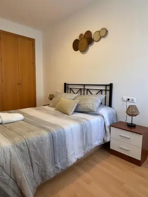 a bedroom with a bed and a table with a clock on the wall at El Mirador de Inés - Primera Línea de Playa in El Puerto de Santa María