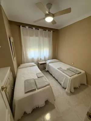a bedroom with two beds and a ceiling fan at Chalet en La Barrosa, Piscina+BBQ+Grifo de Cerveza in Chiclana de la Frontera