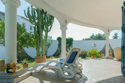 a white chair sitting on a patio under a gazebo at Villa La Contenta jardín y piscina en Conil centro in Conil de la Frontera