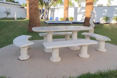 a picnic table and two benches in a park at Villa La Contenta jardín y piscina en Conil centro in Conil de la Frontera