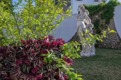 a statue of a woman standing next to a plant at Villa La Contenta jardín y piscina en Conil centro in Conil de la Frontera