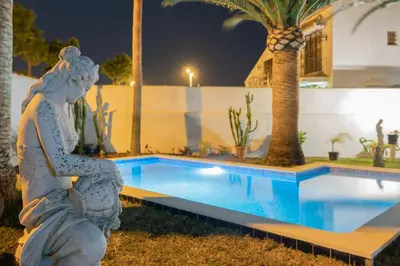 a statue of a mermaid sitting next to a swimming pool at Villa La Contenta jardín y piscina en Conil centro in Conil de la Frontera