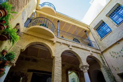 an old building with a balcony in a courtyard at LalaSuites SHARIS in Jerez de la Frontera