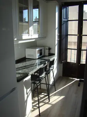 a kitchen with a counter with two chairs and a microwave at Apartamento Luz de Sanlúcar in Sanlúcar de Barrameda