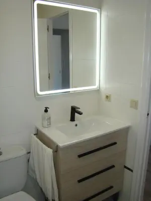 a bathroom with a sink and a mirror and a toilet at Apartamento Luz de Sanlúcar in Sanlúcar de Barrameda