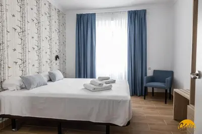 a bedroom with a bed and a blue chair at La Luz de la Viña - by Cadiz Time in Cádiz