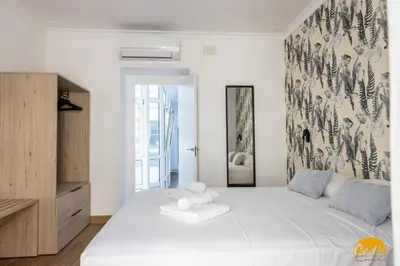 a white bedroom with a large white bed and a mirror at La Luz de la Viña - by Cadiz Time in Cádiz