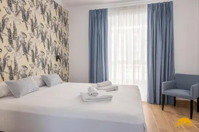 a bedroom with a large white bed and a chair at La Luz de la Viña - by Cadiz Time in Cádiz
