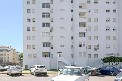 a large white building with cars parked in a parking lot at Valdelagrana: primera línea de playa. in El Puerto de Santa María