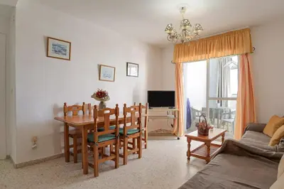 a living room with a table and chairs and a television at Valdelagrana: primera línea de playa. in El Puerto de Santa María