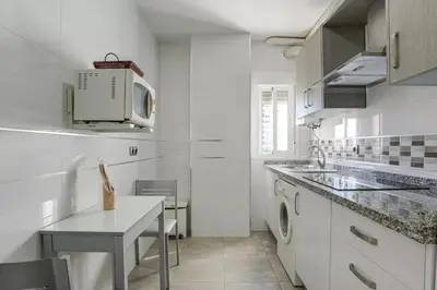 a white kitchen with a sink and a microwave at Valdelagrana: primera línea de playa. in El Puerto de Santa María