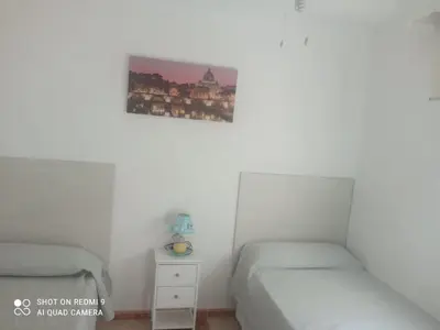 a bedroom with two beds and a picture on the wall at Apartamento grumete in El Puerto de Santa María