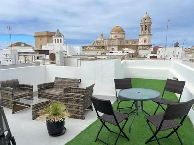 a patio with chairs and a table on a roof at Hidden Gem Penthouse El Mesón in Cádiz