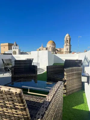 a patio with chairs and tables on a roof at Hidden Gem Penthouse El Mesón in Cádiz