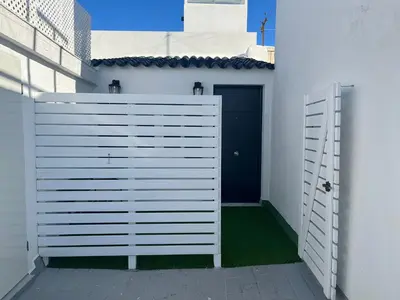 a white fence in front of a blue door at Hidden Gem Penthouse El Mesón in Cádiz
