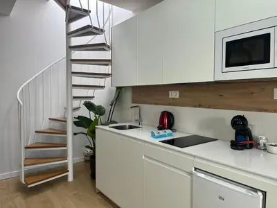 a kitchen with white cabinets and a spiral staircase at Hidden Gem Penthouse El Mesón in Cádiz
