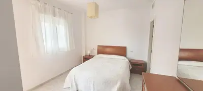 a white bedroom with a bed and a mirror at Casa Playa de Valdelagrana in El Puerto de Santa María