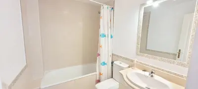 a bathroom with a sink and a toilet and a mirror at Casa Playa de Valdelagrana in El Puerto de Santa María