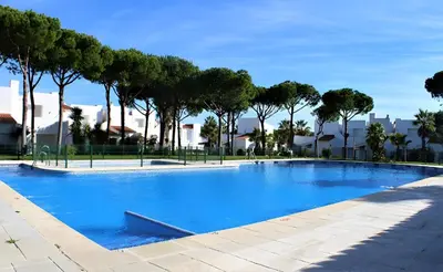 a large blue swimming pool with trees in the background at Casa en Loma Sancti Petri a 900 m de la playa de La Barrosa in Chiclana de la Frontera