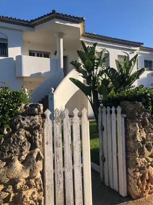 a white fence in front of a house at Calma La Barrosa Apartamento in Chiclana de la Frontera