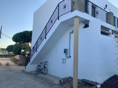 a bike parked next to a white building with a staircase at Conil Colorado 1 rústico y económico in Conil de la Frontera