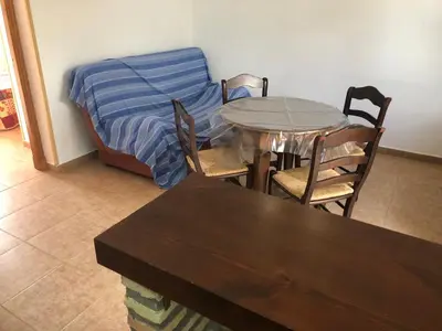 a dining room with a table and chairs and a bed at Conil Colorado 1 rústico y económico in Conil de la Frontera