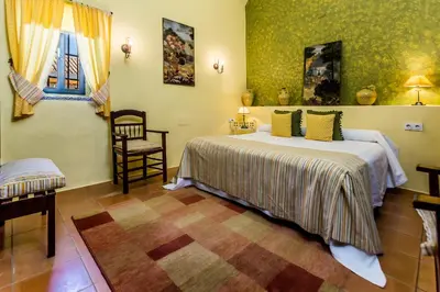a bedroom with two beds and a chair in it at Hacienda El Santiscal in Arcos de la Frontera