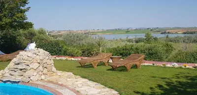 a group of benches sitting next to a swimming pool at Hacienda El Santiscal in Arcos de la Frontera