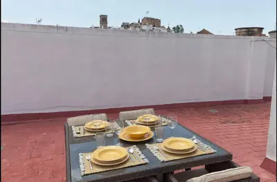 a table with yellow plates and glasses on a patio at Precioso y luminoso apartamento Calle Corredera. Casco Histórico in Arcos de la Frontera