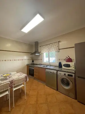 a kitchen with a washing machine and a table with chairs at CASA SUROESTE in Conil de la Frontera