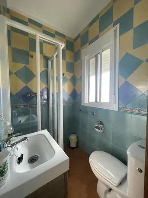 a bathroom with a sink and a toilet and a window at CASA SUROESTE in Conil de la Frontera