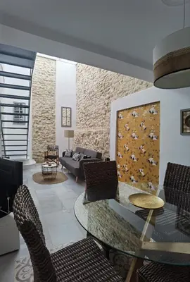 a living room with a glass table and chairs at Ático Plaza 9 by casitasconencantoes in Medina Sidonia