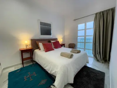 a bedroom with a large bed with red pillows and a window at Las Marinas de la Bahia in Cádiz