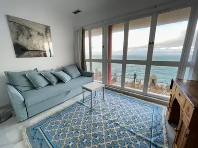 a living room with a blue couch and a large window at Las Marinas de la Bahia in Cádiz