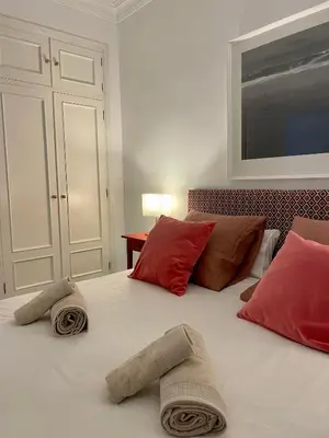 a white bed with red pillows on top of it at Las Marinas de la Bahia in Cádiz