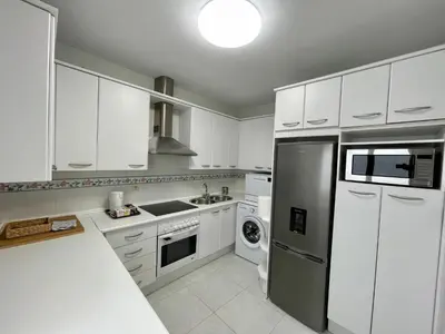 a kitchen with white cabinets and a stainless steel refrigerator at Las Marinas de la Bahia in Cádiz