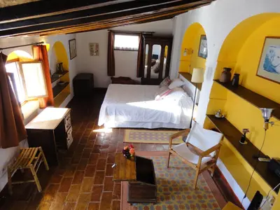 a bedroom with a bed and a chair in a room at La Casa Grande in Arcos de la Frontera