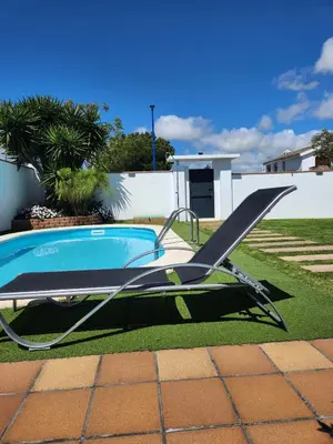 a swimming pool with a chair in a yard at Minichalet Jacaranda in Chiclana de la Frontera