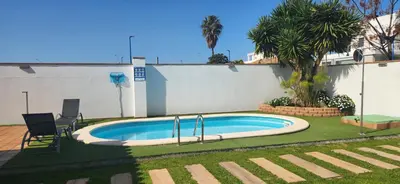 a swimming pool with two chairs in a yard at Minichalet Jacaranda in Chiclana de la Frontera