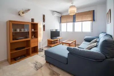 a living room with a blue couch and a television at Apartamento Tribalia Cadiz in Cádiz