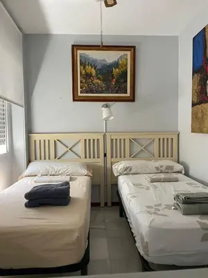 a bedroom with two beds and a picture on the wall at Magnífico piso en la playa in El Puerto de Santa María