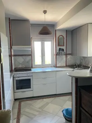 a kitchen with white cabinets and a window at Magnífico piso en la playa in El Puerto de Santa María