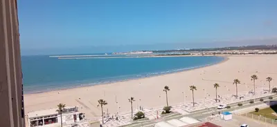 a view of a beach with palm trees and the ocean at Valdelagrana vista al mar Puerto de Santa María in El Puerto de Santa María